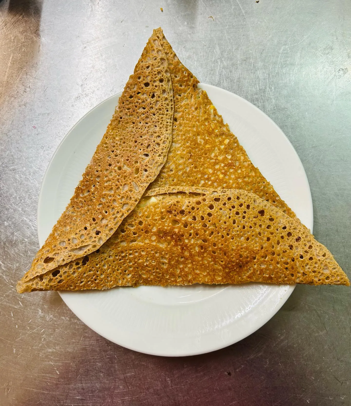 La galette La Chaumière, pliée en triangle, sur une assiette blanche