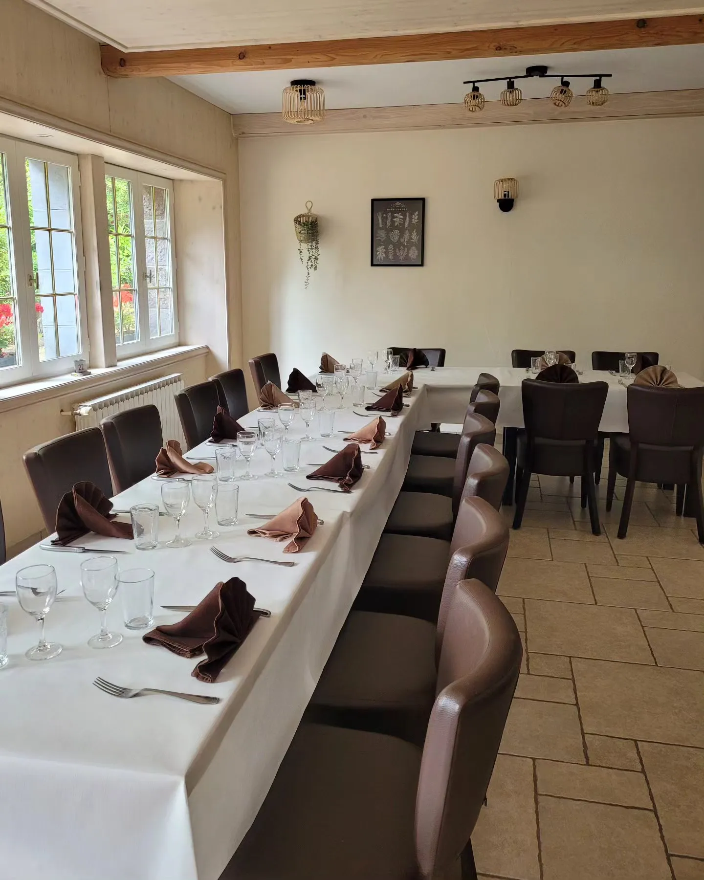 La salle de l’auberge avec une longue table dressée pour un groupe