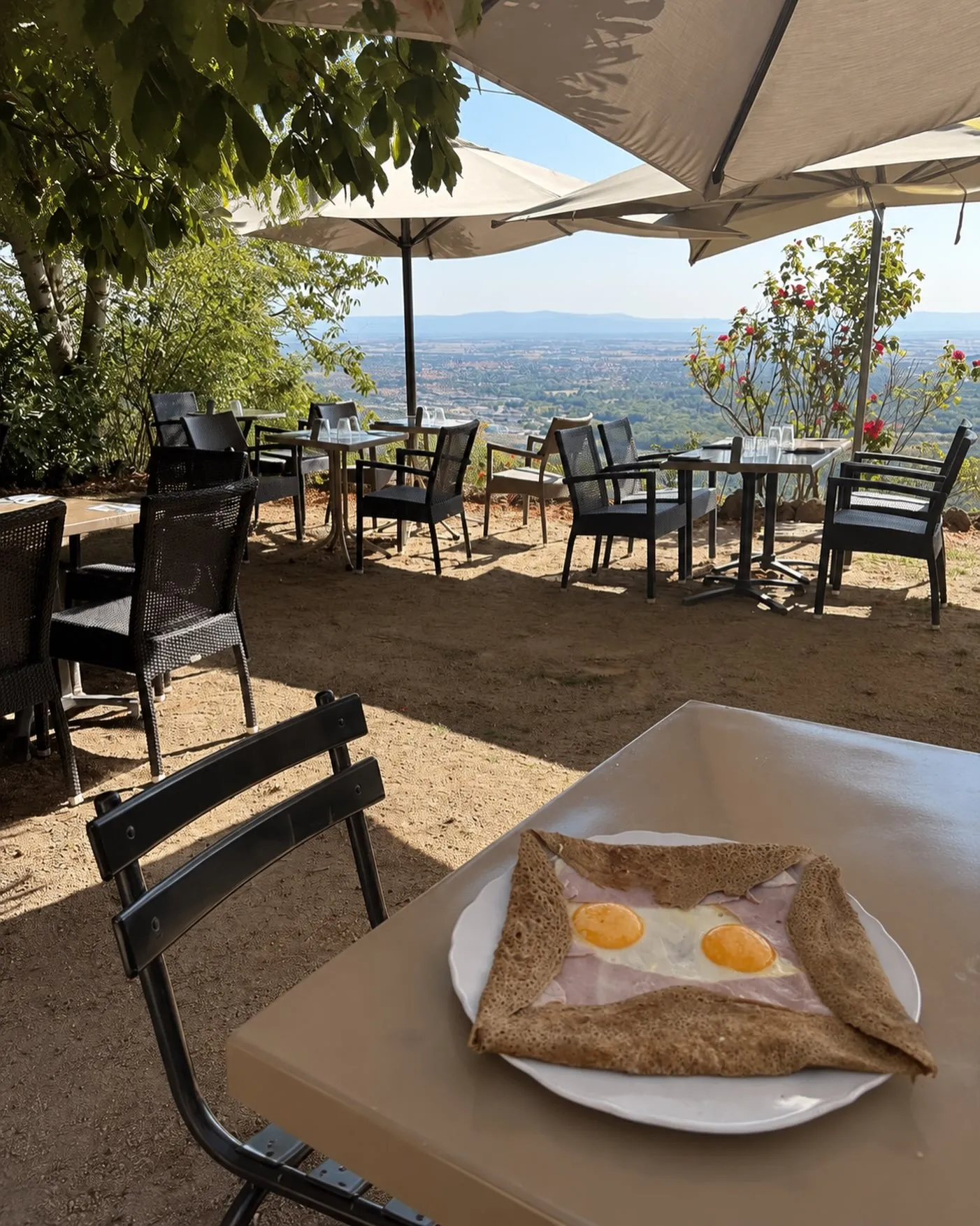 Une galette complète servie sur la terrasse, sous les parasols, face à la plaine de Limagne